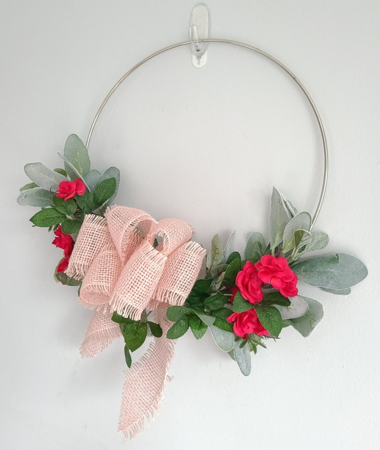 Rosa blommor och grågröna blad med rosa rosett på en grå metallring