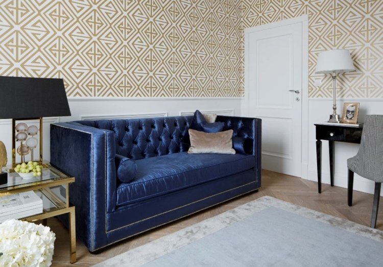 mörkblå soffa med quiltning och guldnitar och tillbehör