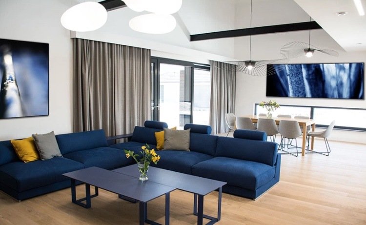 blå soffa i det moderna vardagsrummet med kuddar i grått och gult kombinerat