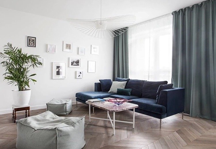 Mörkblå soffa i det skandinaviska vardagsrummet med parkettgolv i chevronmönster