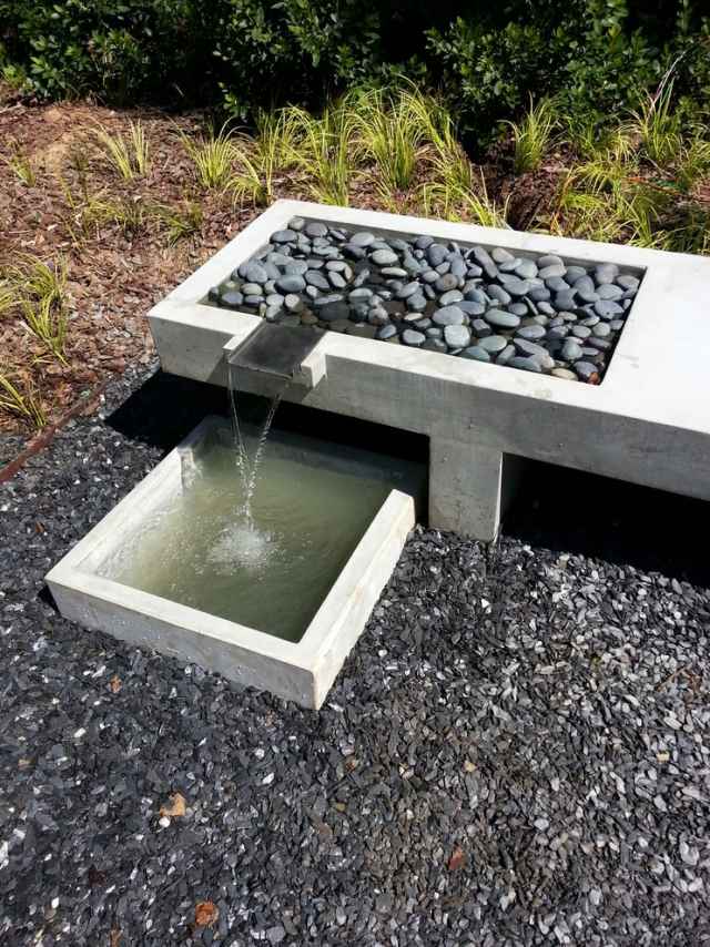 modernt bakgårdshus trädgård fontän grus betongmonument