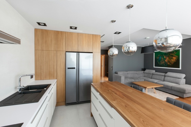 Vita köksskåp och träytor, kombinerat med inbyggt kylskåp i silver