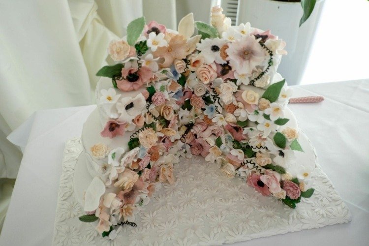 Skivad bröllopstårta med blommig dekoration och en vacker tårtplatta
