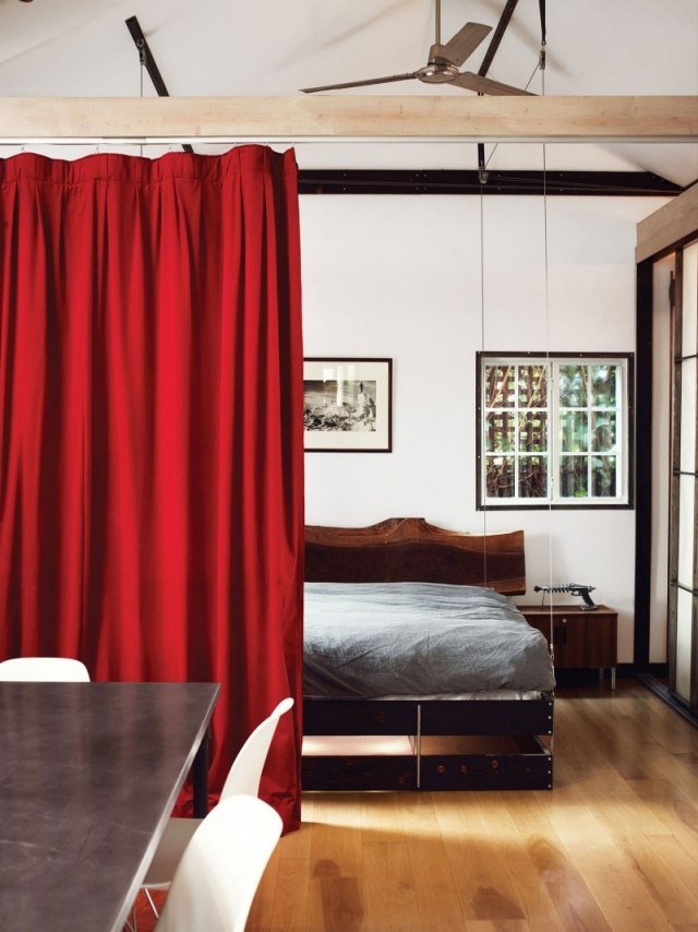 liten lägenhet säng filt ner röd gardin