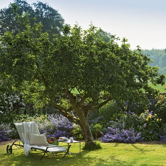 Trädgårdslounge för att koppla av i en idyllisk solstol i trädskugga