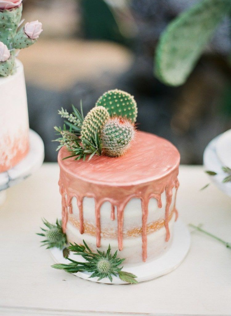 Enkla små bröllopstårtor på en nivå med droppglasyr i koppar och kaktusar