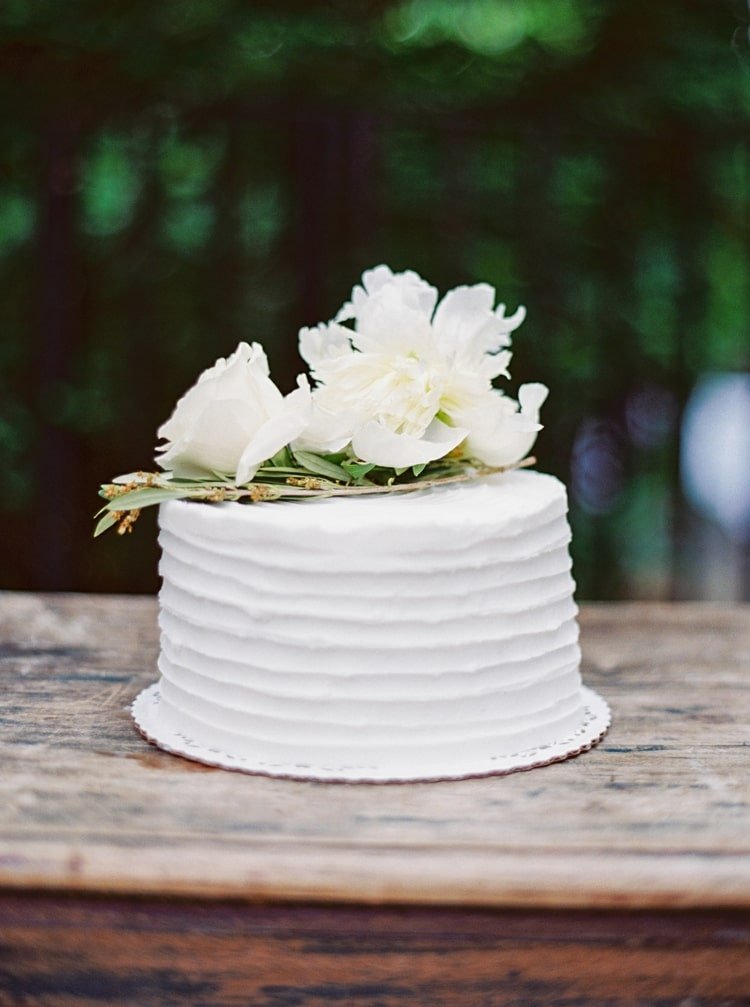 Vit tårta för bröllopet i en rifflad look med vita blommor