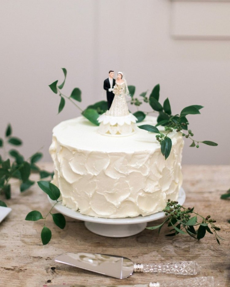Designa enkla små bröllopstårtor på en nivå med en tårtfigur och grönska