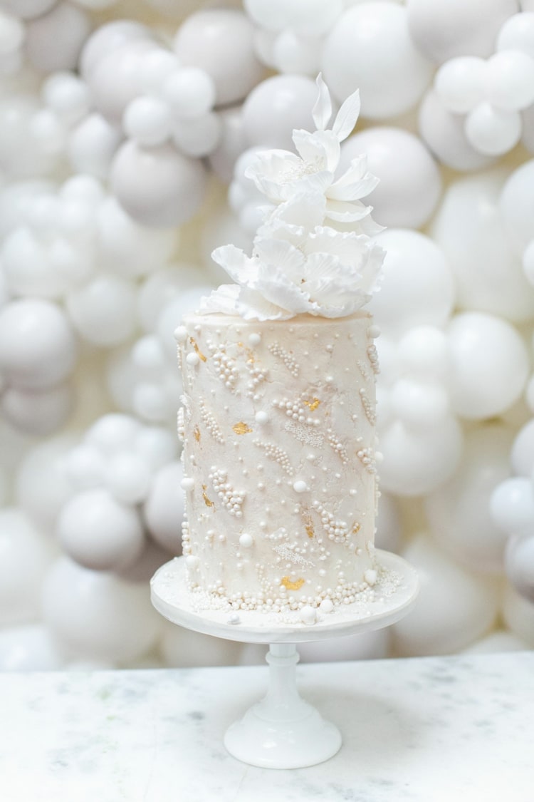En-cylindrisk tårta i vitt dekorerad med pärlor