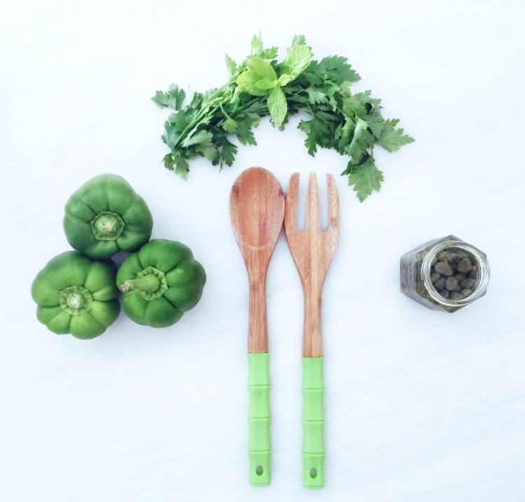 träsked och gaffel för matlagning bredvid friska grönsaker som grön paprika och persilja