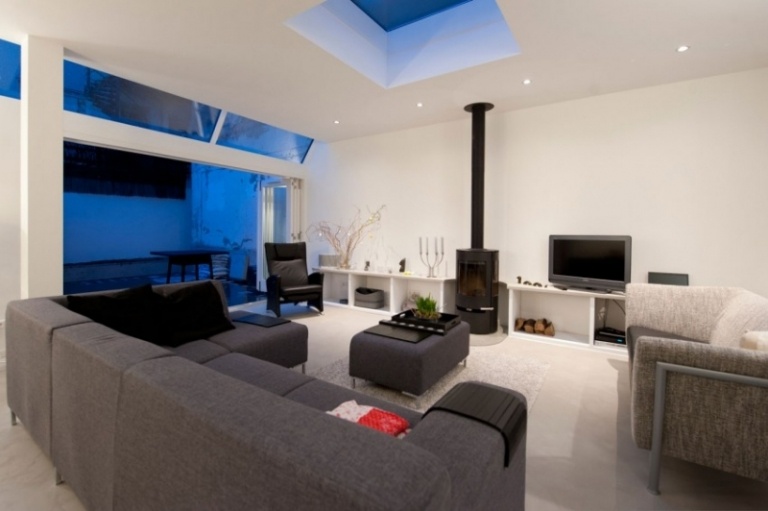 Möbler för vardagsrummet -vita soffor-grå-öppen spis-svart-takfönster-trädgårdsfönster