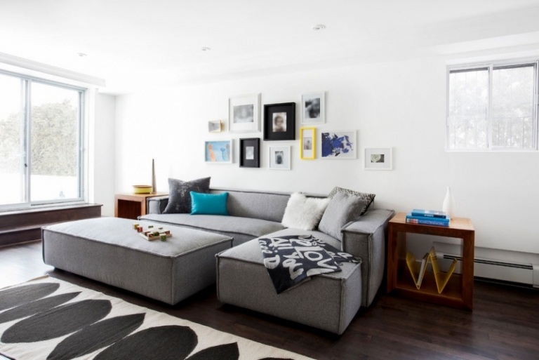 Inredning-vardagsrum-soffa-stora-grå-bilder-vägg-vit-fönster-trägolv-mörk