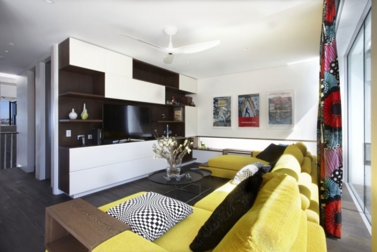 Inredning-vardagsrum-senap-gul-svart-vit-tv-väggridåer-färgglada-mönster-affischer-soffbord