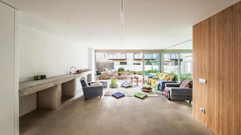 Inredning-vardagsrum-öppet-utrymme-modern-soffa-fåtölj-golv-kuddar-färgade-betong-golv-väggbeklädnad-trä
