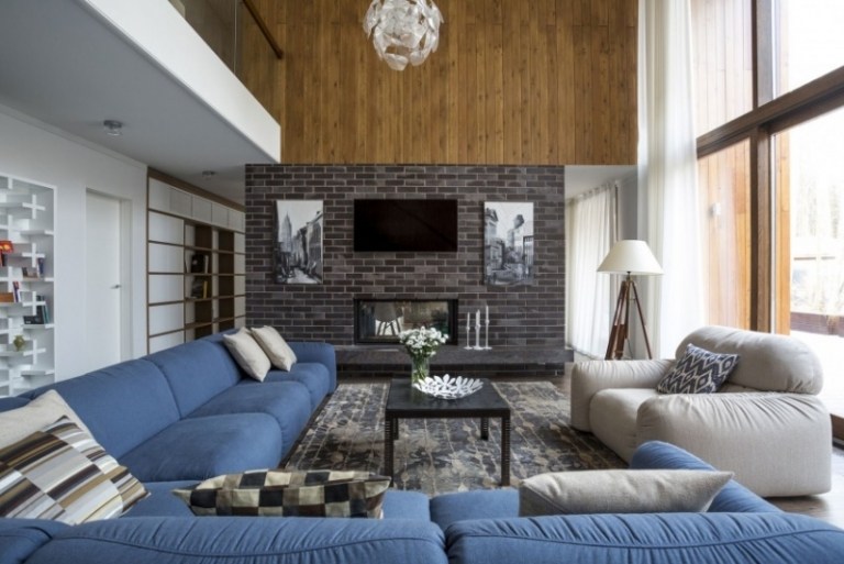 Inredning-vardagsrum-hörnsoffa-stor-blå-matta-används-look-fåtölj-grå-väggbeklädnad-trä-tegel-lampa-dekoration