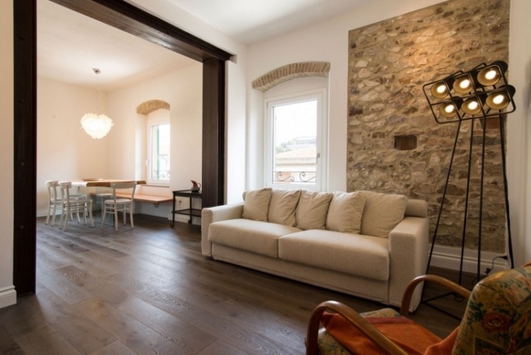 Inredning-vardagsrum-gammal-ny-stil-mix-soffa-grå-fåtölj-antik-lampa-sten-vägg-vit-gips