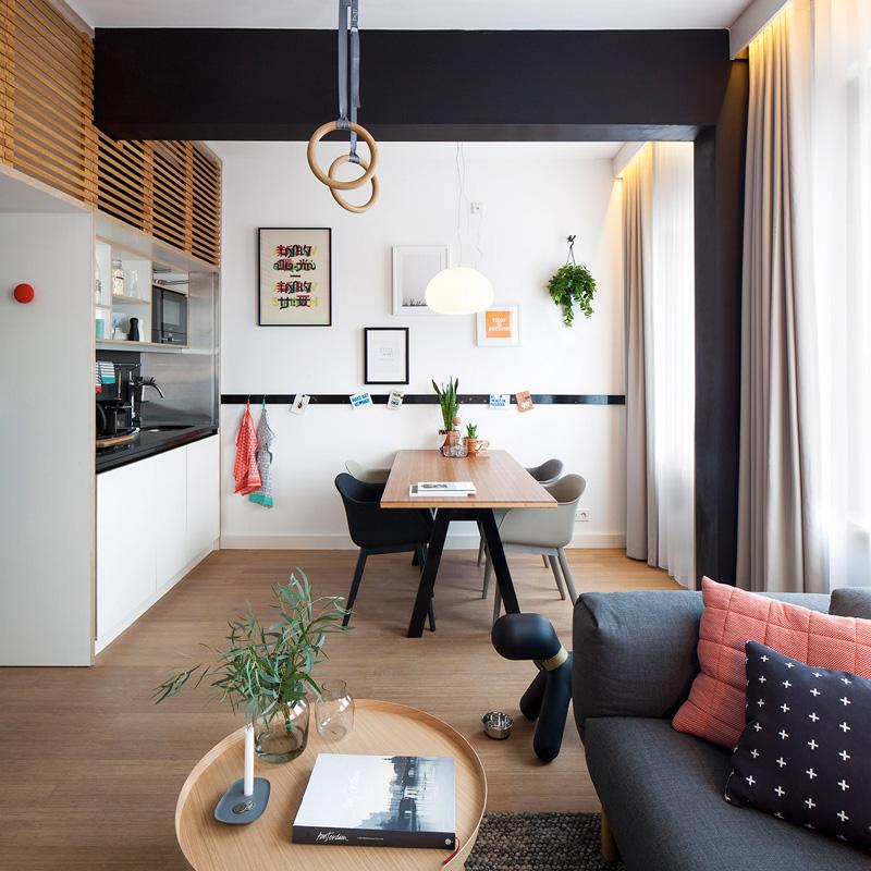 Designa en ettrumslägenhet -funktionell-soffa-kök-matbord-stolar-gymnastikringar-svart-vitt-vanligt trägolv