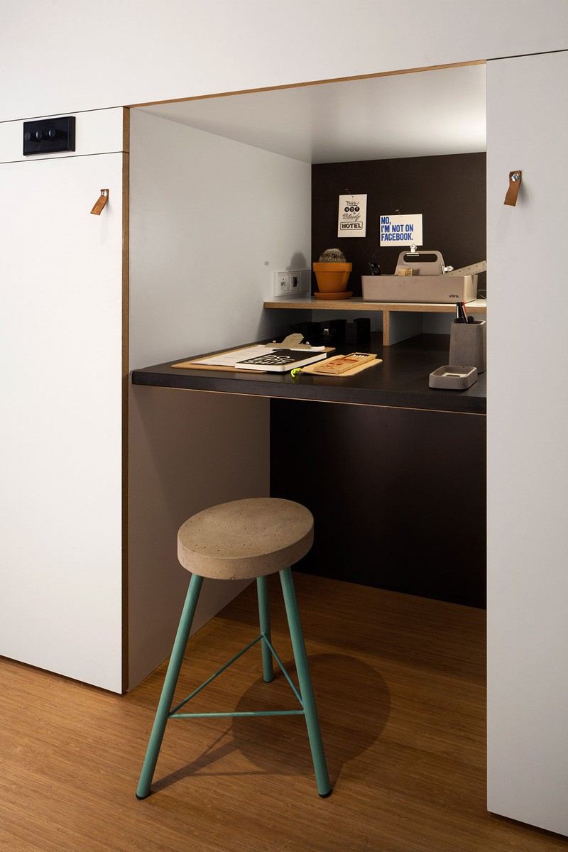 Designa en enrumslägenhet -funktionell-praktisk-gömd-arbetsplats-skrivbord-pall-belysning-trägolv-vit
