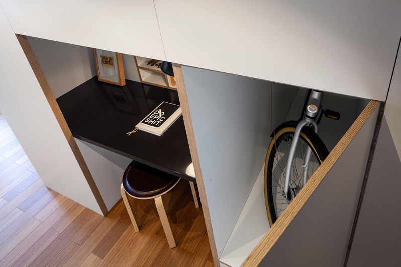 en-rums-lägenhet-design-funktionalitet-skåp-skrivbord-pall-cykel-vitt-trä-praktiskt