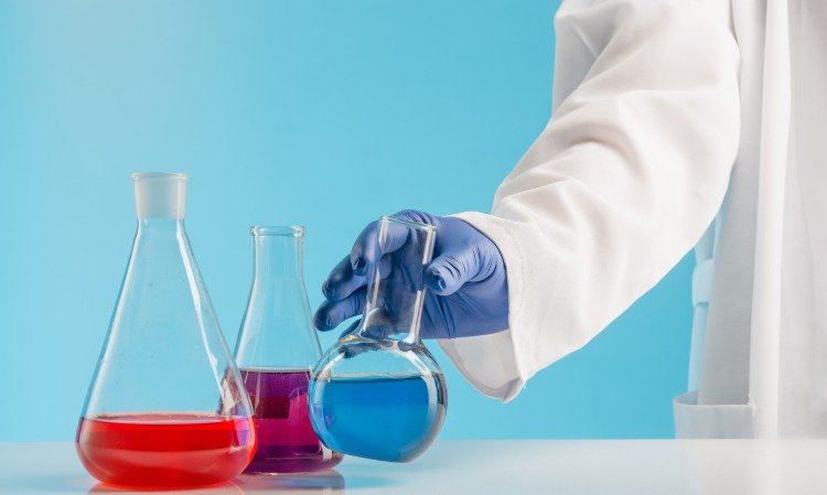 Forskare i laboratoriet undersöker färgade vätskor med gummihandskar