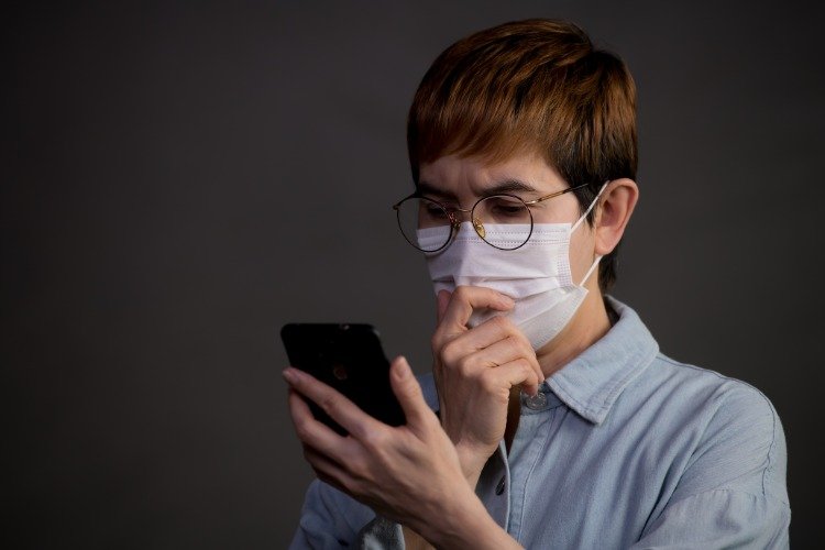 rädsla för coronavirus använder mobiltelefon med skyddsmask