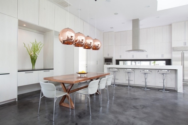 Inbyggt kök, vita, handtagslösa främre hängande lampor, blanka kopparutseende matbord