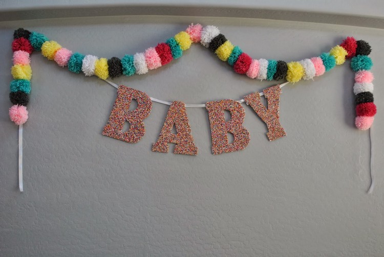 baby shower idéer väggdekoration pompongkrans färgglada bebisbokstäver