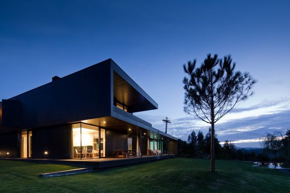 designerhus av svart och mörkt byggmaterial vid solnedgången