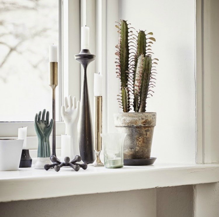 Dekorera fönsterbrädan - ljushållare, statyer och kaktusar i en kruka