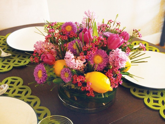 Blommor bukett citroner-i mitten av bordet