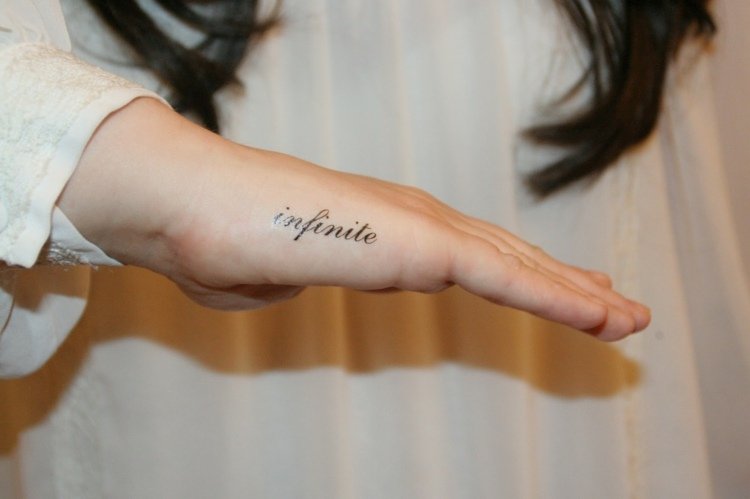 finger-tatuering-lilla finger-skriva-i sidled-gränslös-kvinna-hand-svart