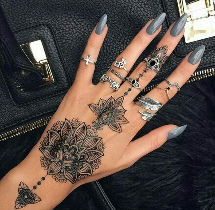 finger-tatuering-mandala-dekorationer-långfinger-ringar-nagellack-grå-handväska