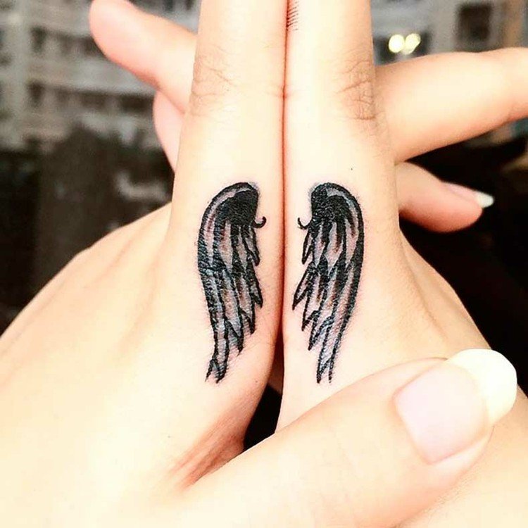 finger-tatuering-ängel-vingar-svart-pekfinger-kvinna-händer-i sidled