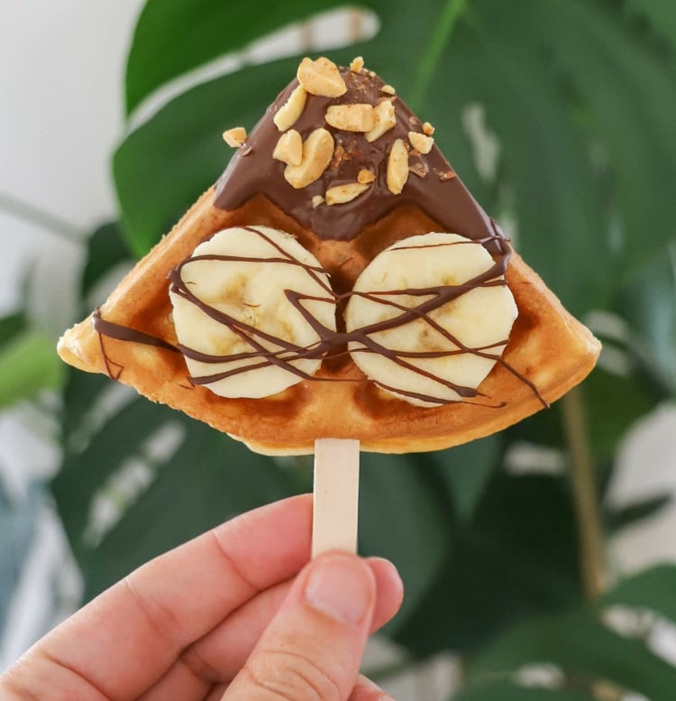 Spett kvartade våfflor på popsicle -pinnar och toppa med choklad, banan och jordnötter