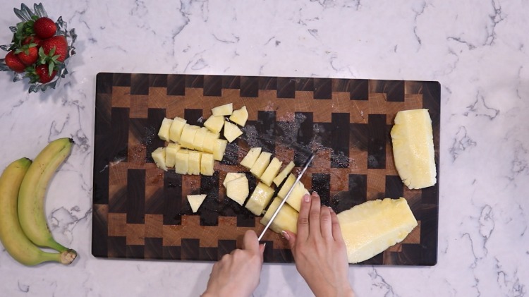 jordgubbar bananer och ananas skuren i bitar på köksbrädan