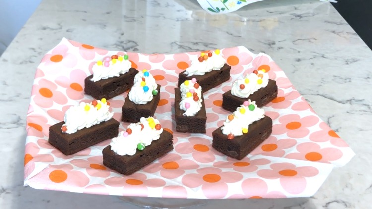 färgglada chokladkakor med en glasyr av vispad grädde och sockerpärlor på en servett