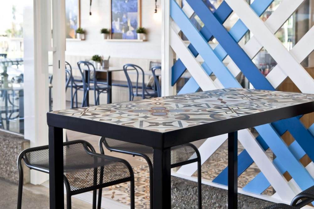 långt bord i caféet med en svart träram och en yta av färgade plattor