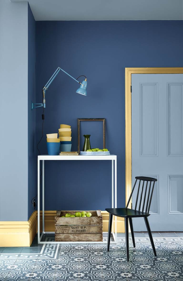 Himmelblå entrédörr och blå vägg och dörrkarm i gult skapar ett attraktivt färgschema i korridoren
