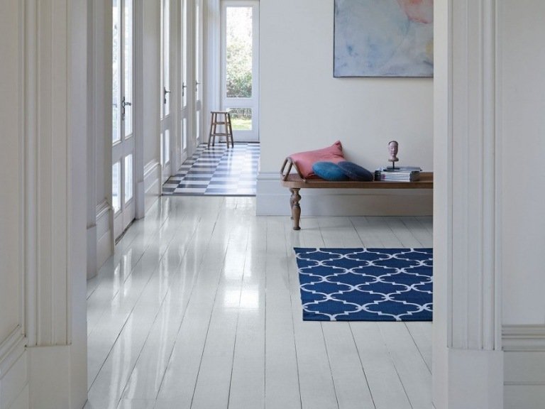 Benvita väggar och mörkblå matta i hallen i skandinavisk stil