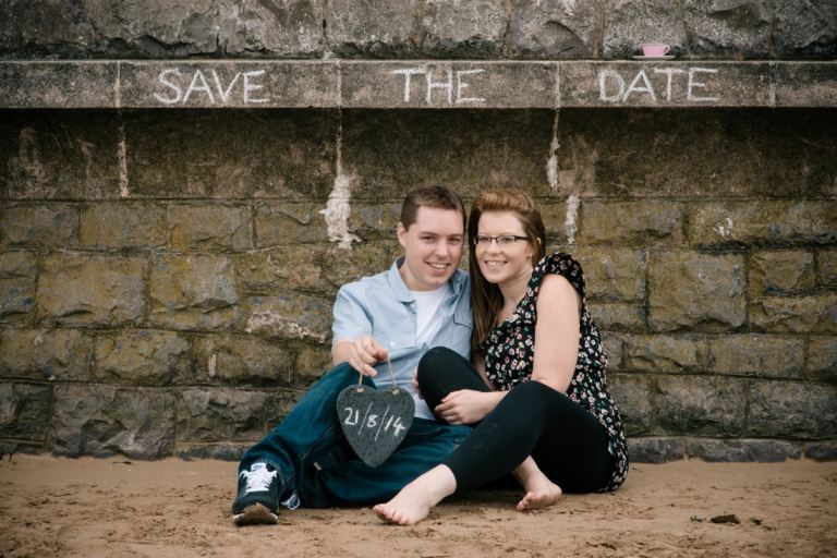 Förlovad poserar framför en vägg med det planerade äktenskapsdatumet