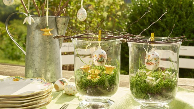 Designa glasbehållare med mossa och häng påskägg på grenar i glasen