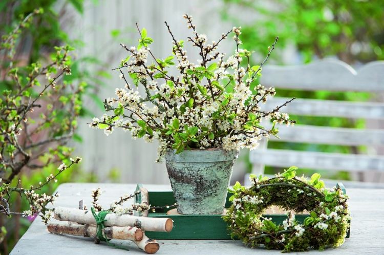 Grön dekoration för våren med blommande grenar, björkgrenar och en krans av mossa