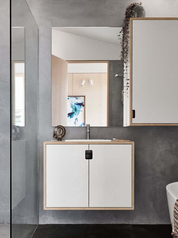 grå exponerad betong i badrummet med spegel och vägg i vita färger