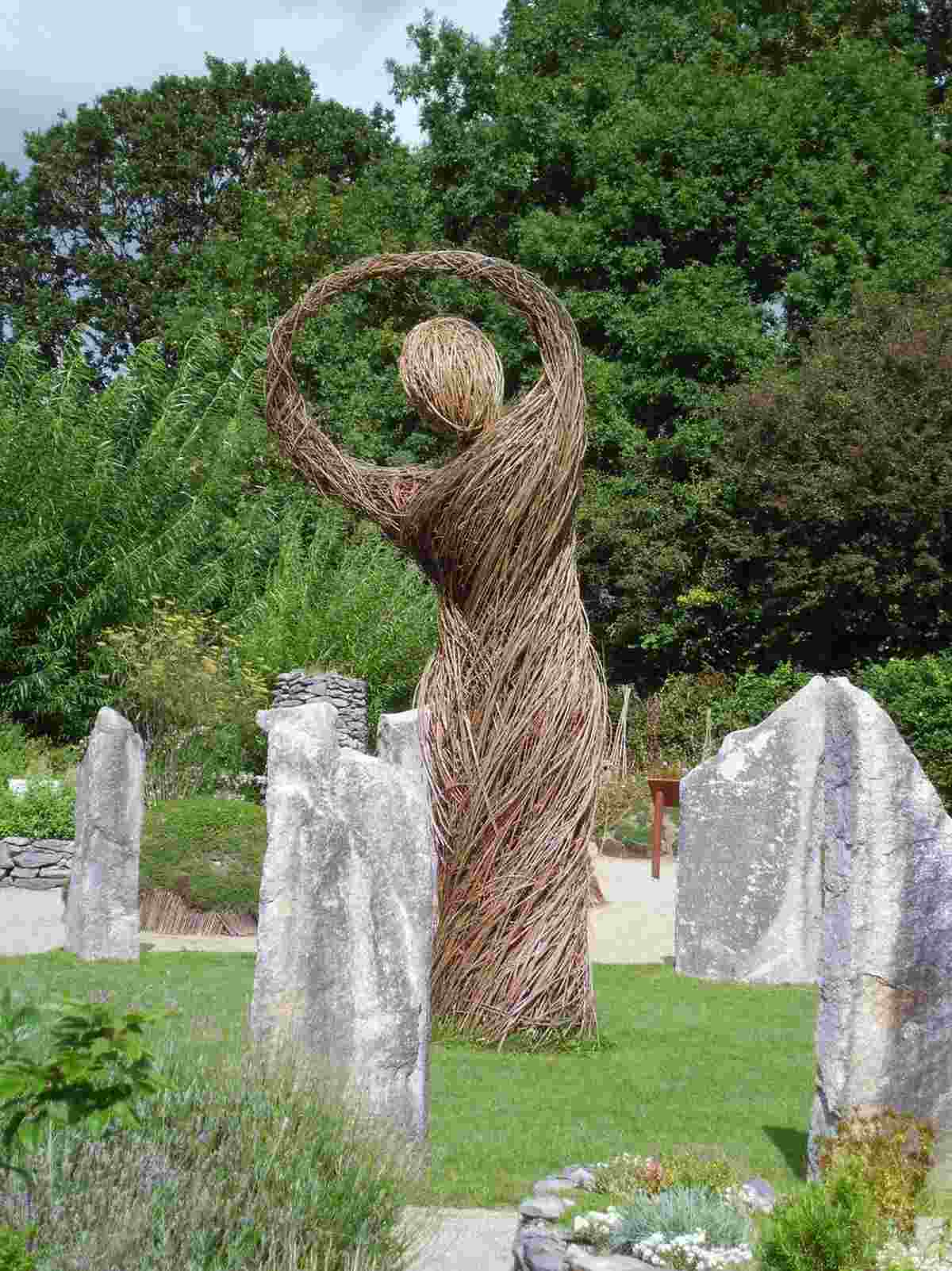placera en kvinnofigur av grenar som mittpunkten i trädgården bredvid stenar