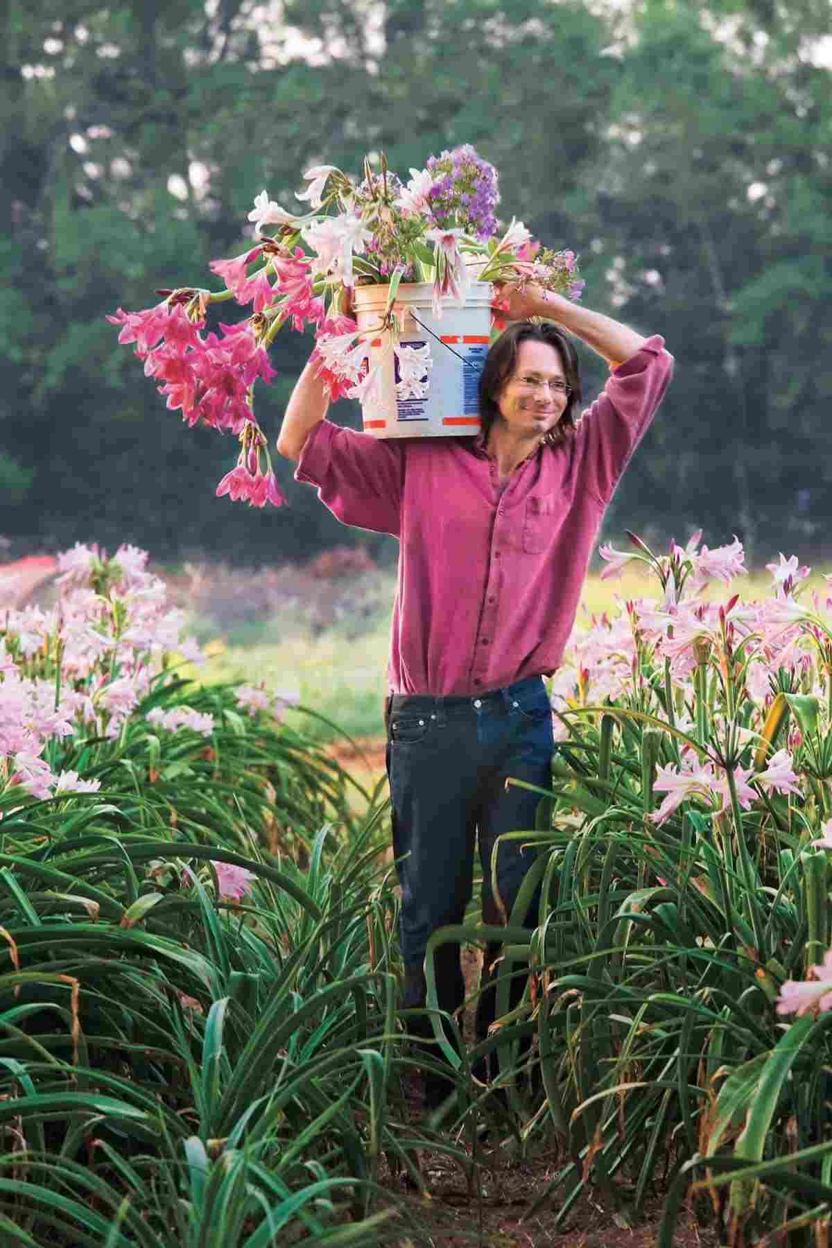 Som trädgårdsmästare bär mannen en hink full med blommor att plantera