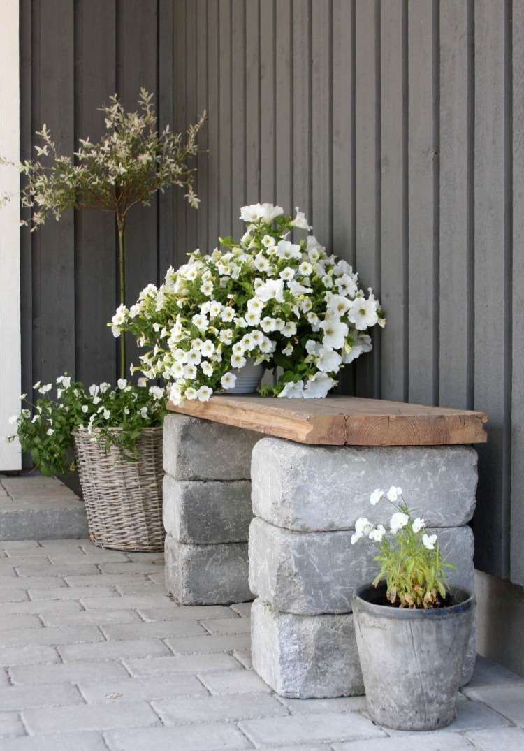 gamla betongblock och trä som material för en bänk i trädgården med blommor