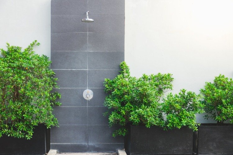 minimalistisk design för utomhusdusch med grå kakel och gröna växter som accent i trädgårdsdesignen