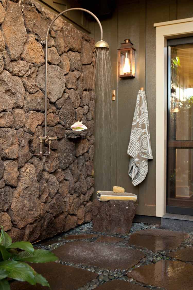utomhusdusch med stenväggar i rustik stil med sittkrokar och lykta för mer komfort