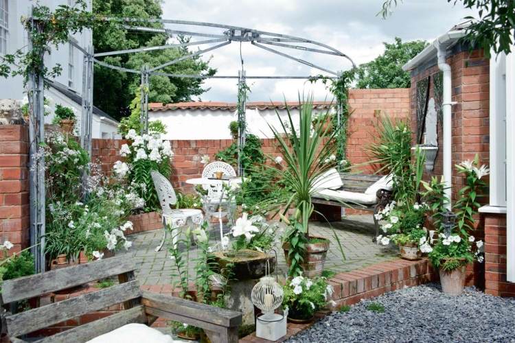 trädgård design-liten-trädgård-terrass-aluminium-pergola-vita-blommor-röd-tegel-vägg