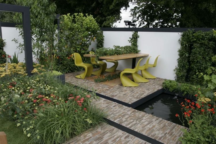 Trädgårdsdesign med trä-matbord-väggmonterade-gröna-växter-stolar-damm